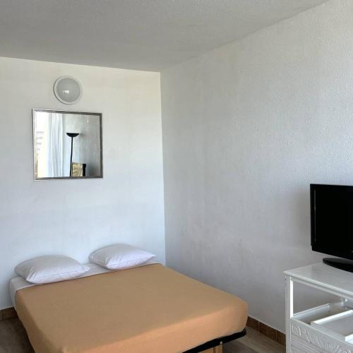 Cette petite chambre comprend un lit et une télévision. dans l'établissement Studio Héliopolis E 27 - 2 personnes, au Cap d'Agde