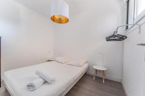 Cette petite chambre blanche comprend un lit et une table. dans l'établissement Appartement vue mer et Parking, à Palavas-les-Flots