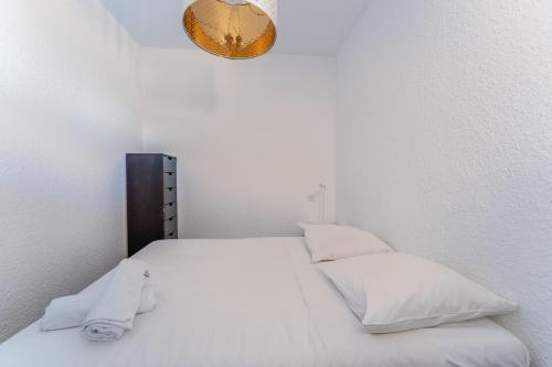 - un lit blanc avec des oreillers blancs et un miroir dans l'établissement Appartement vue mer et Parking, à Palavas-les-Flots