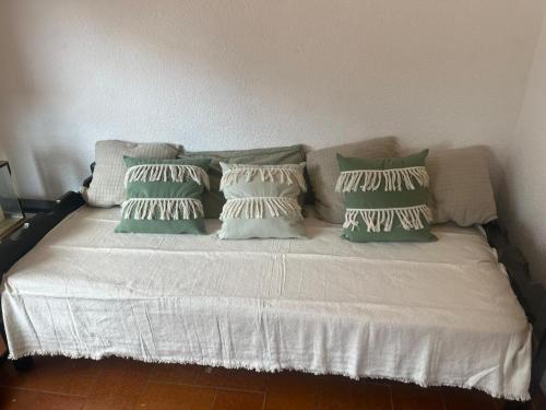 a white bed with green pillows on it at Pinamar para 5 a 100 metros del mar con garage in Pinamar