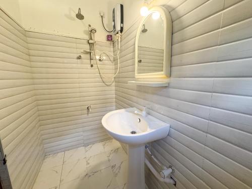 a white bathroom with a sink and a mirror at SIlvas Surf Home in Weligama