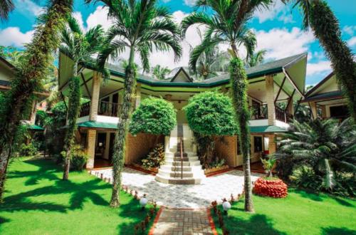 a house with palm trees in front of it at Boracay Paradise Garden Hotel By Tripzy Fun in Boracay