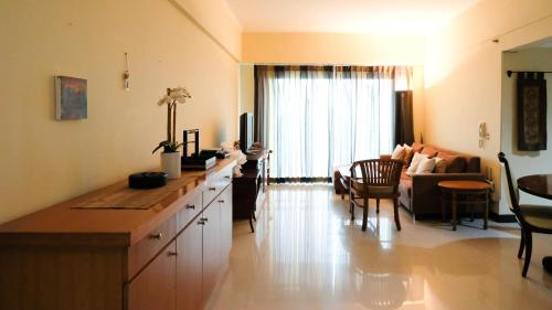 a kitchen and living room with a couch and a table at Extra Spacious and Homey 2BR at Kondominium Puncak Marina Apartment By Travelio in Surabaya
