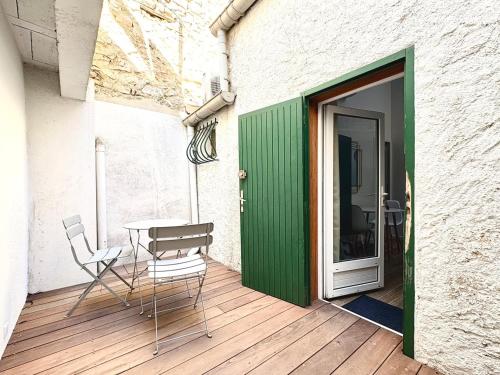d'une terrasse avec une table, des chaises et une porte verte. dans l'établissement Le Studio des Tilleuls, Climatisé & Vrai Lit, à Nîmes