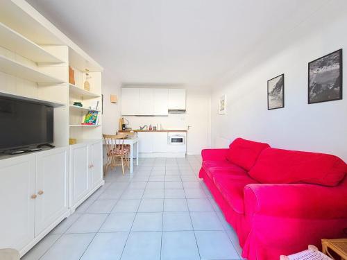 un salon avec un canapé rouge et une cuisine dans l'établissement Appartement de plain pied Le Racou Mar 24, à Argelès-sur-Mer