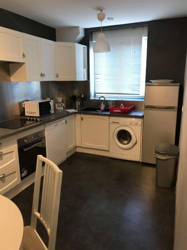 une cuisine avec des armoires blanches et une machine à laver dans l'établissement Maison Digard CHERBOURG, à Cherbourg en Cotentin