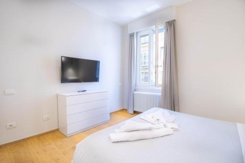 a white bedroom with a tv and a bed at Vicino al mare Centro, AC con ascensore in Civitanova Marche