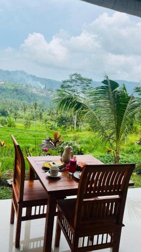 a wooden table and chairs with a view of a field at Sarwhe Nadi Homestay in Sidemen