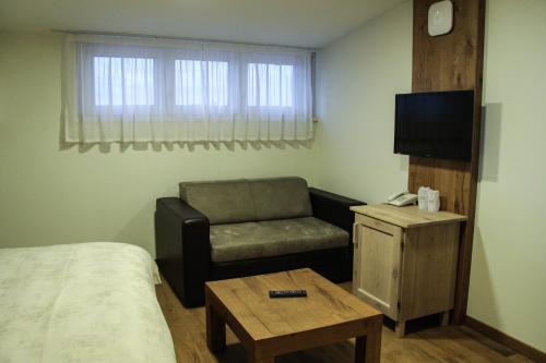 a room with a bed and a chair and a television at B&B Villa Panuka in Pančevo