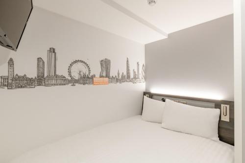 a bedroom with a white bed with a drawing on the wall at easyHotel Victoria in London