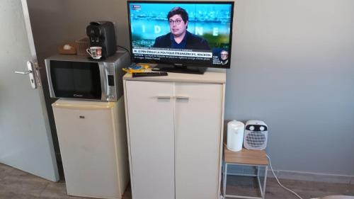 une télévision installée au-dessus d'un meuble blanc avec une télévision dans l'établissement Chambre Green, à Dunkerque