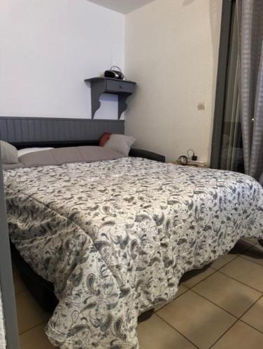 une chambre avec un lit avec une couverture dessus dans l'établissement Studio Loggia Mas de la Pinède parking, à Valras-Plage