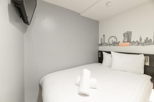 a bedroom with a white bed with white pillows at easyHotel Victoria in London