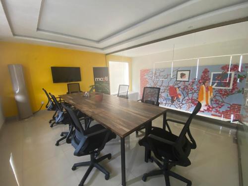 a conference room with a wooden table and chairs at Maati Spaces - Rooms with Kitchen in Lahore