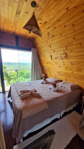 une chambre avec un grand lit avec un plafond en bois dans l'établissement Cabana Vila Suíça, à Pedro II