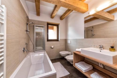 a bathroom with a tub and a toilet and a sink at Appartement Treffpunkt in Molini di Tures