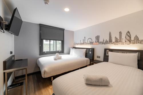 a hotel room with two beds and a tv at easyHotel Victoria in London