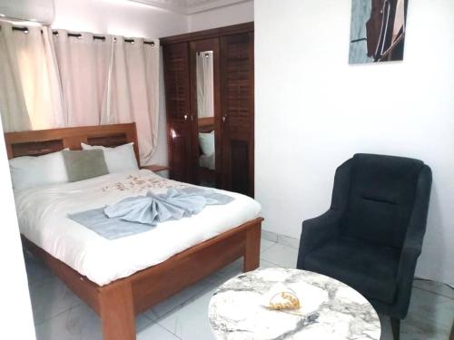 a bedroom with a bed and a black chair at Bi-Hotel 1 in Dakar