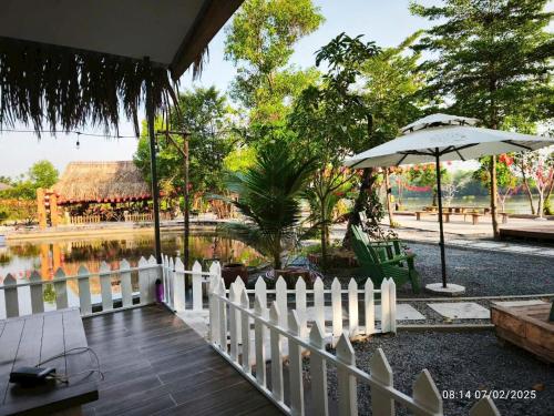 a white fence and an umbrella next to a pond at Homestay Mẹ Khang 2 - Phòng view Sông in Cu Chi