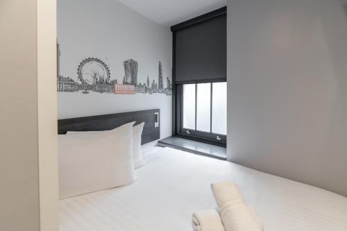 a bedroom with white walls and a large window at easyHotel Victoria in London