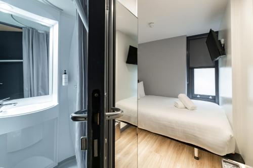a small room with a bed and a mirror at easyHotel Victoria in London