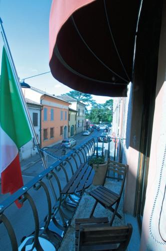 a group of chairs and an umbrella on a balcony at Alkimia Smart Rooms in Ferrara