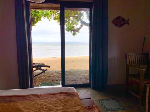 a bedroom with a view of the beach through a sliding glass door at Libertalia Hotel in Sainte Marie