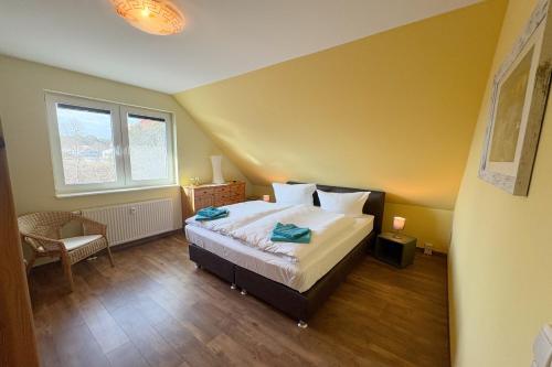 een slaapkamer met een bed, een stoel en een raam bij Cölpinstrasse Ferienwohnung Ostseeblume in Kolpinsee