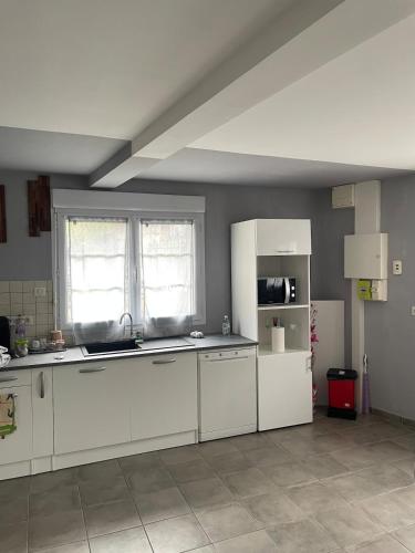  La cuisine est équipée de placards blancs et d'un réfrigérateur. dans l'établissement Maison agréable de 51 m2, à Cuts