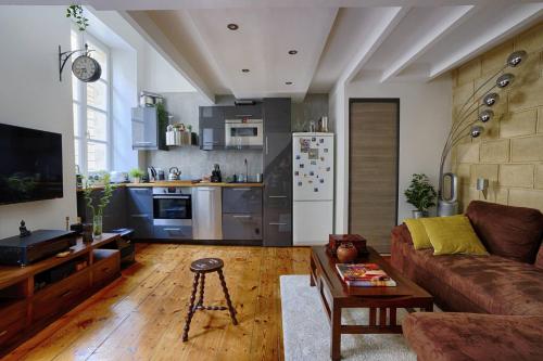 un salon avec un canapé et une cuisine dans l'établissement Jolie duplex au cœur de saint Michel, à Bordeaux