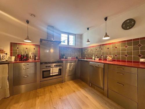 une cuisine équipée d'appareils en acier inoxydable et d'une horloge murale. dans l'établissement Le Saint Antoine, Centre Ville, 2 chambres, Clim, à Nîmes