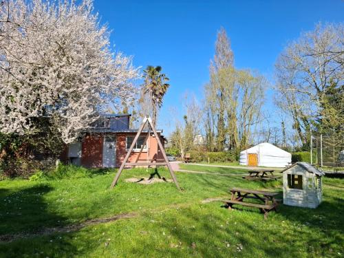 a park with a playground and a picnic table and a tent at Le Village Insolite yourte et roulotte in Saint-Benoît-des-Ondes
