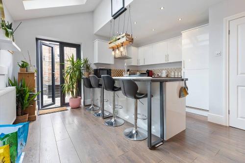 a kitchen with a bar with stools in it at Stunning terraced house next to York Racecourse in York