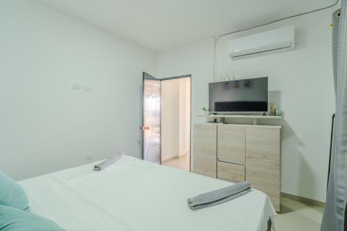 une chambre blanche avec un lit et une télévision dans l'établissement Apartamentos el mochilero Rural la Boquilla, à Carthagène des Indes
