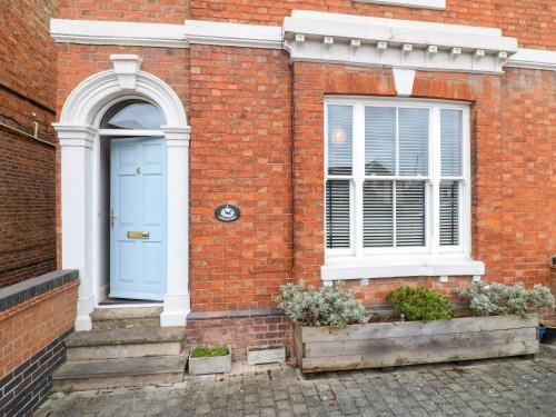 a brick house with a blue door and a window at Molly's Way in Melton Mowbray