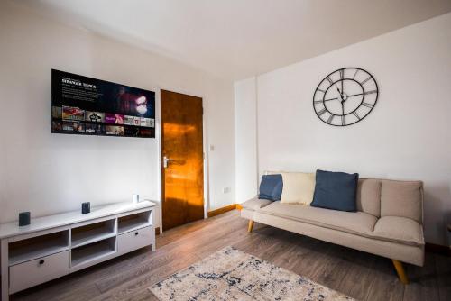 a living room with a couch and a clock on the wall at Spacious 4 Bed with Free Parking in Southampton