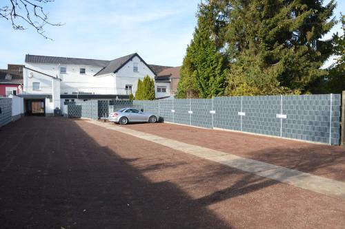 a car parked in a parking lot next to a fence at Pension Zur Traube in Bergheim