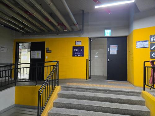 a hallway with stairs and a yellow wall at Ulsan Shimpo KCC Residence in Ulsan