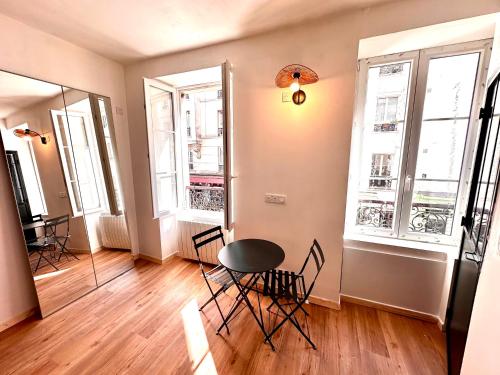 une chambre avec une table, des chaises et deux fenêtres dans l'établissement Sunny Paris studio in the heart of 11ème, à Paris