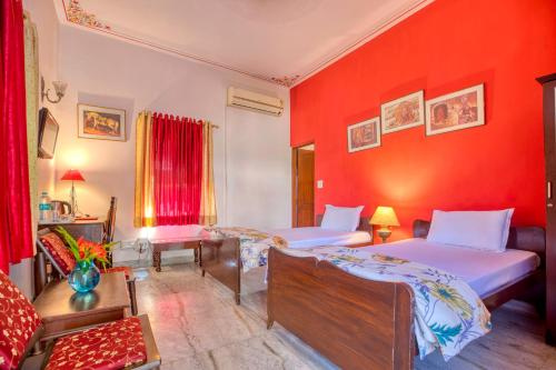 a bedroom with two beds and a red wall at PLAY IKSHANA Hotel in Jaipur