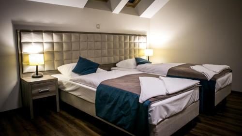 two beds in a hotel room with two lamps at Zajazd Pod Borem in Pokój