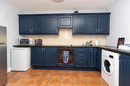 a kitchen with navy blue cabinets and a dishwasher at Seacliff Holiday Homes No 2 by Trident Holiday Homes in Dunmore East