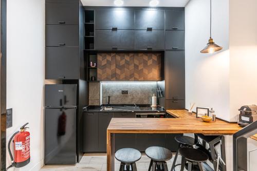 a kitchen with black cabinets and bar stools at CC Atocha Apartments in Madrid