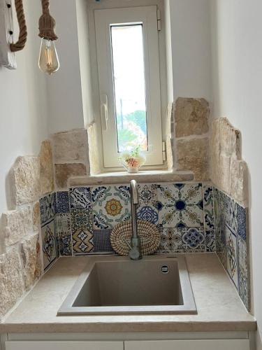 a sink in a kitchen with a window and tiles at Trulli San Pietro in Putignano