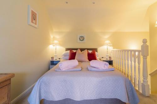 a bedroom with a white bed with two pillows at Acorn Cottage in Quorndon