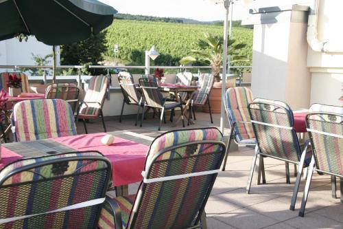 an outdoor patio with tables and chairs with a vineyard at Winzerhaus Johannisberg - Weingut Michael Gietz in Geisenheim
