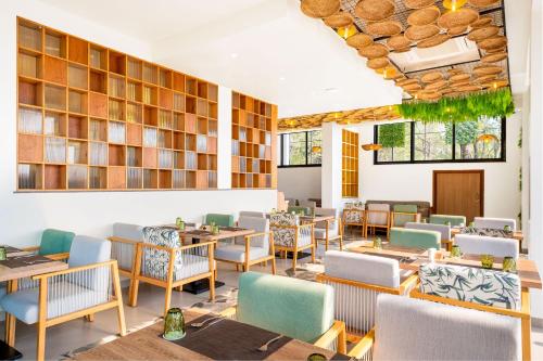 a dining room with tables and chairs and windows at Holitel Anjuna in Arpora