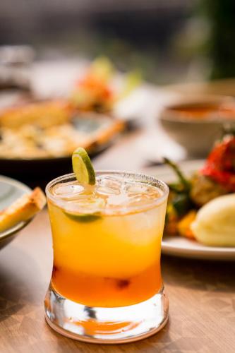 a drink with a lime on a table with plates of food at Holitel Anjuna in Arpora