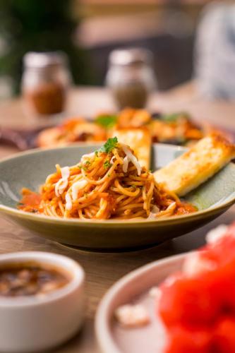 a plate of food with noodles and a slice of pizza at Holitel Anjuna in Arpora
