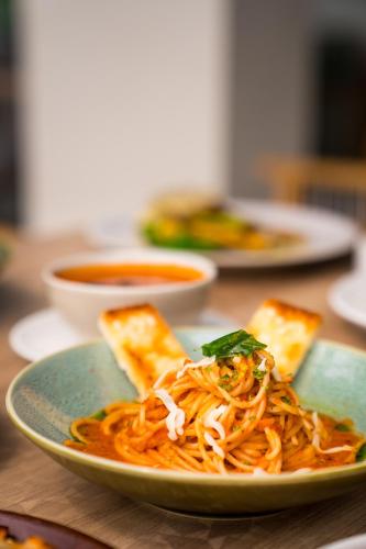 a plate of food with spaghetti and bread on a table at Holitel Anjuna in Arpora